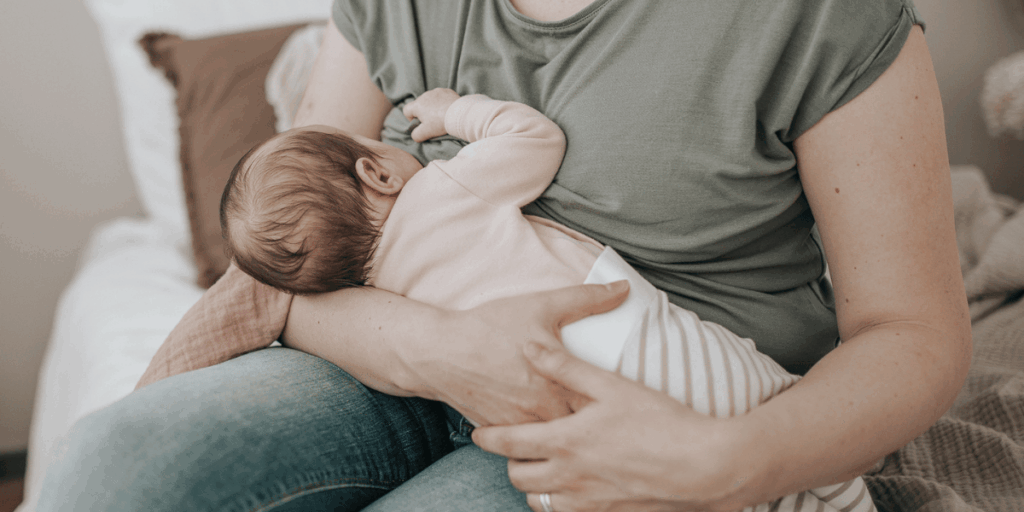 Vauva imemässä rintaa imetyksen aikana, äiti tukee vauvaa rauhallisessa imetysasennossa.