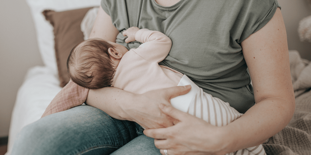 Vauva imemässä rintaa imetyksen aikana, äiti tukee vauvaa rauhallisessa imetysasennossa.